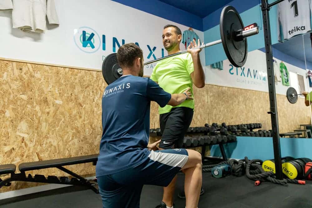 entrenador personal kinaxis ayudando con pesas