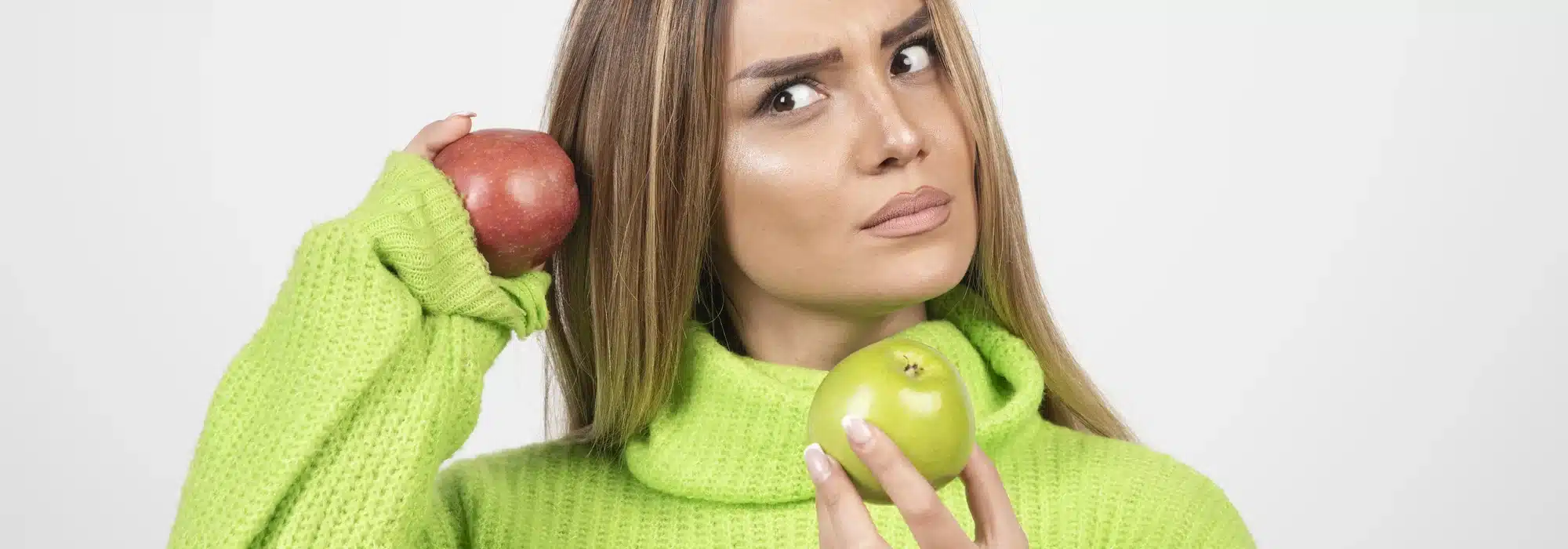 mujer joven camiseta verde sosteniendo dos manzanas arriba